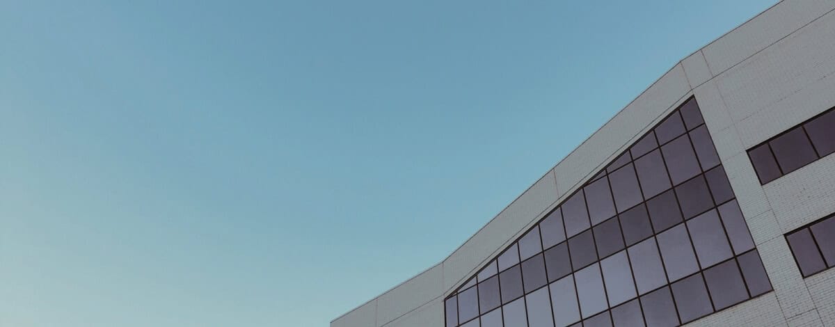 A section of a modern white building with large rectangular windows, set against a clear blue sky.